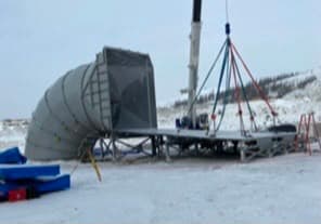 Crane lifting a large fabricated duct elbow on a winter job site